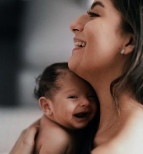 smiling baby held by smiling mother